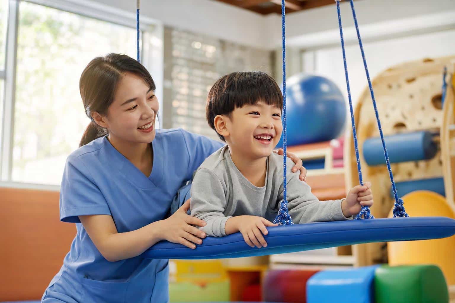 자폐 아동과 작업치료사가 그네에서 놀이하는 모습