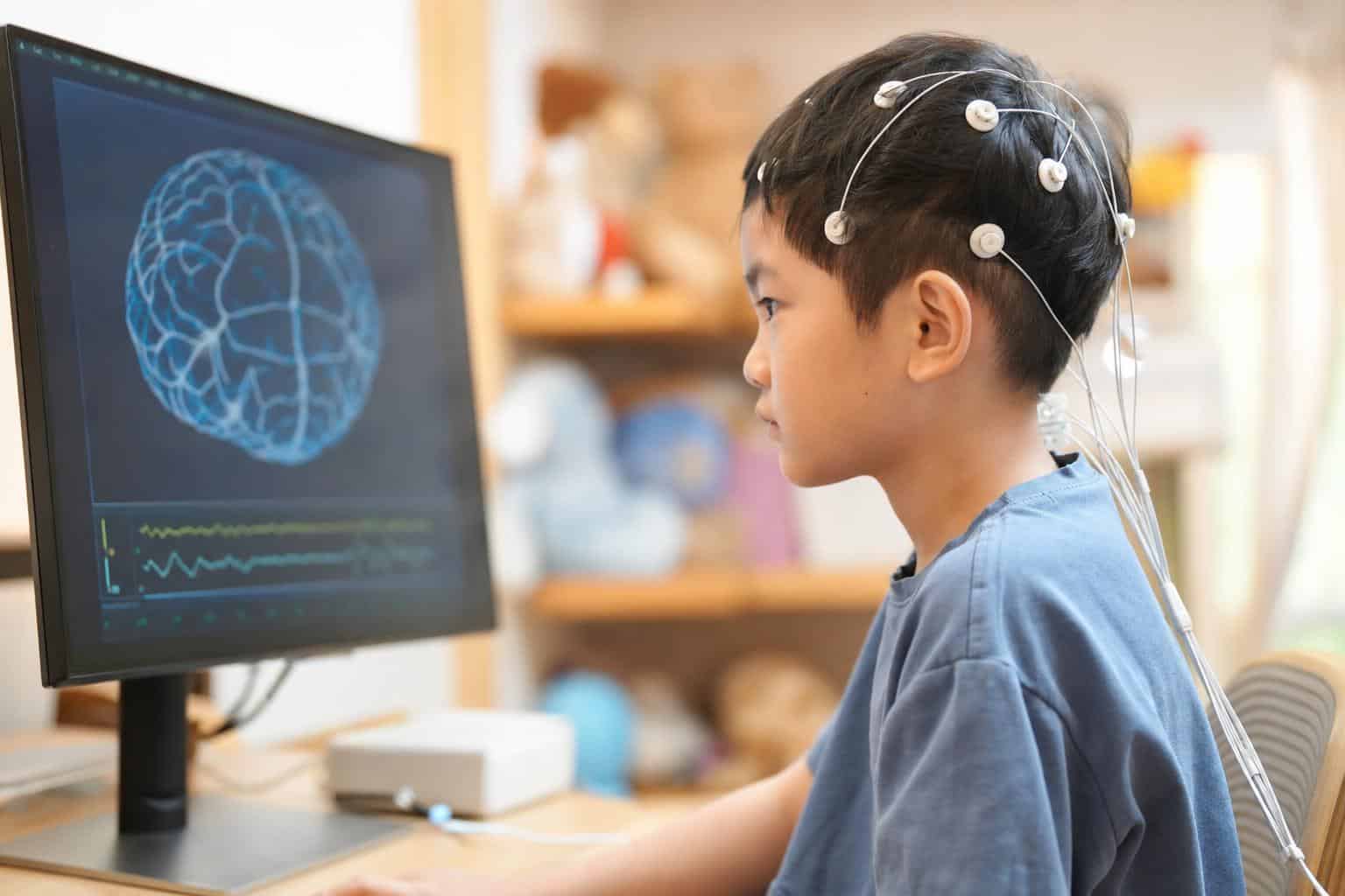 자폐 신경피드백 치료 중인 아동의 모습, EEG 센서를 부착하고 모니터를 집중하는 장면.